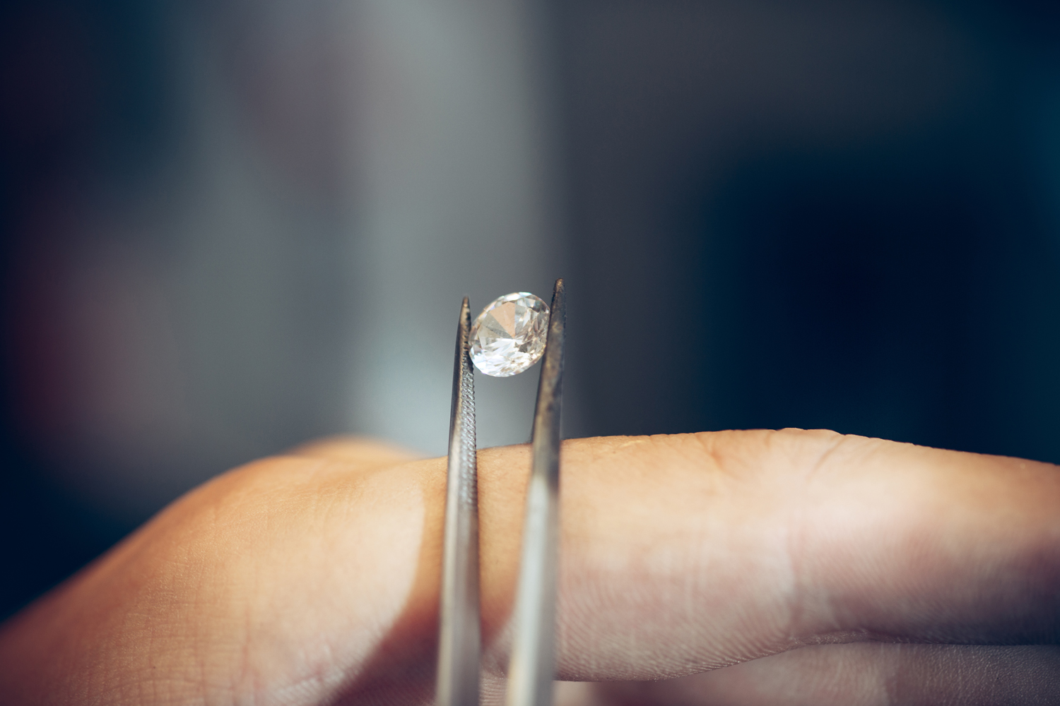 jeweler holding a raw diamond stone with tweezers